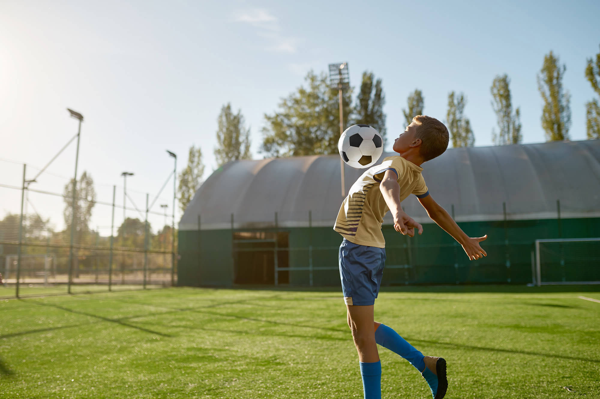 Junior football player jumping to hit soccer ball